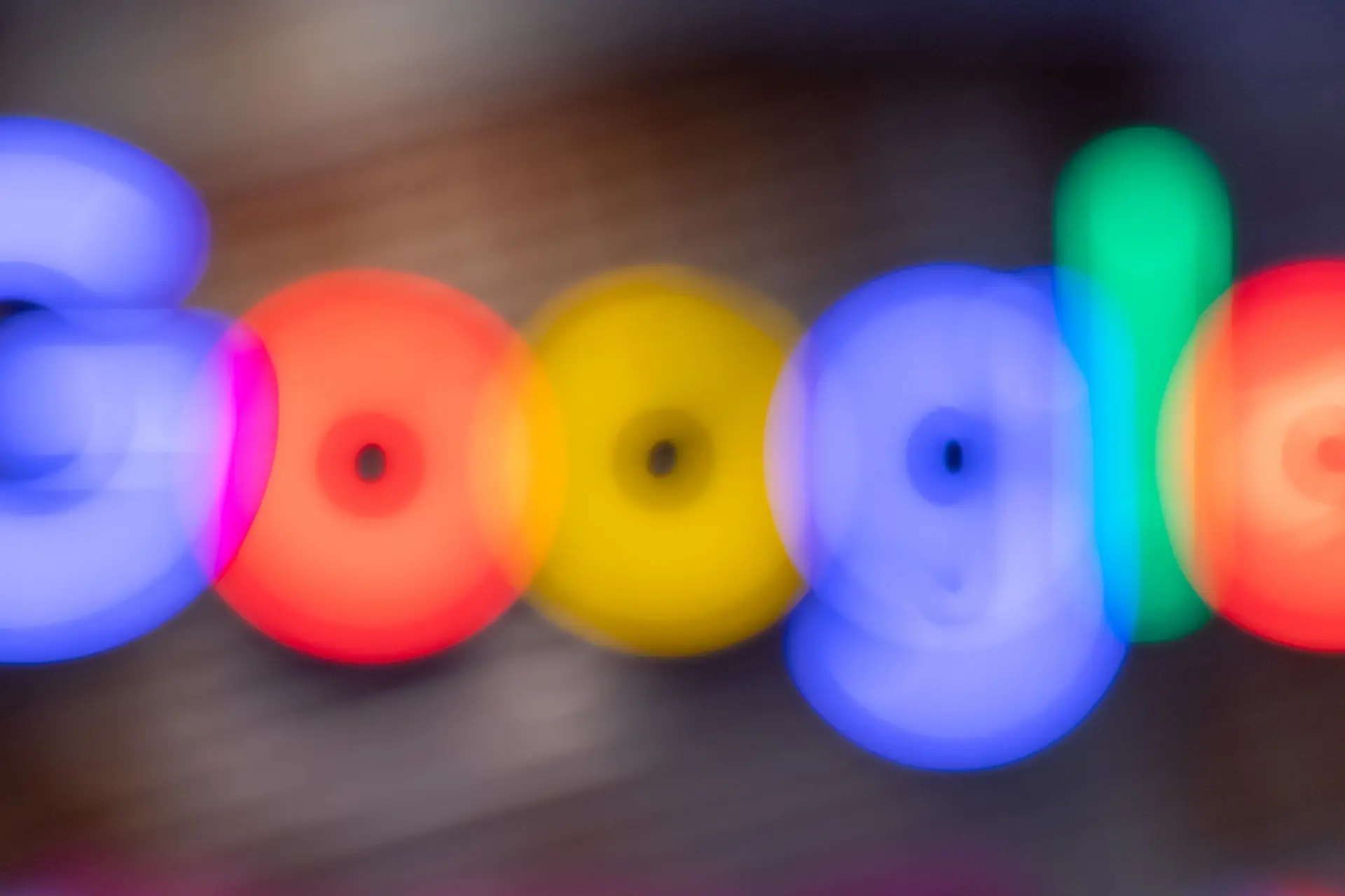Blurry, colorful image showing the Google logo with its distinctive blue, red, yellow, and green letters out of focus against a dark background—perfect for illustrating 2023 SEO trends or Google Ads CPL strategies.